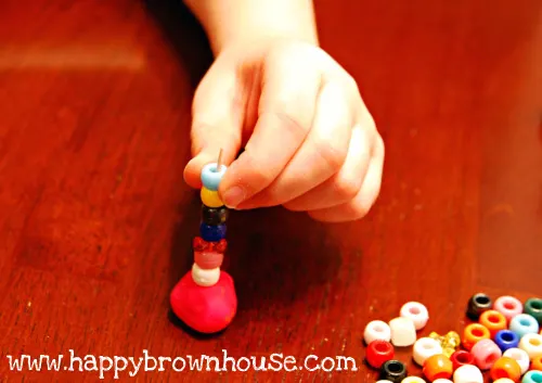 threading beads on a toothpick for playdough fine motor skills practice