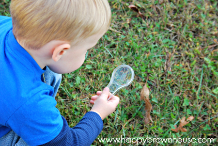 child looking through magnifying glass at grass