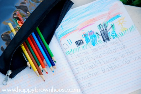 close up of colored pencils and science journal with kid art and handwriting on the page