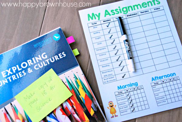 laminated Homeschool Assignment and Chore Chart, dry erase marker, and teacher\'s curriculum book with sticky tabs attached and sticking out of pages