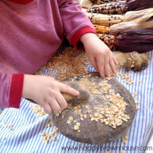 close up of child's hands pounding corn with rocks at a Native American exhibit