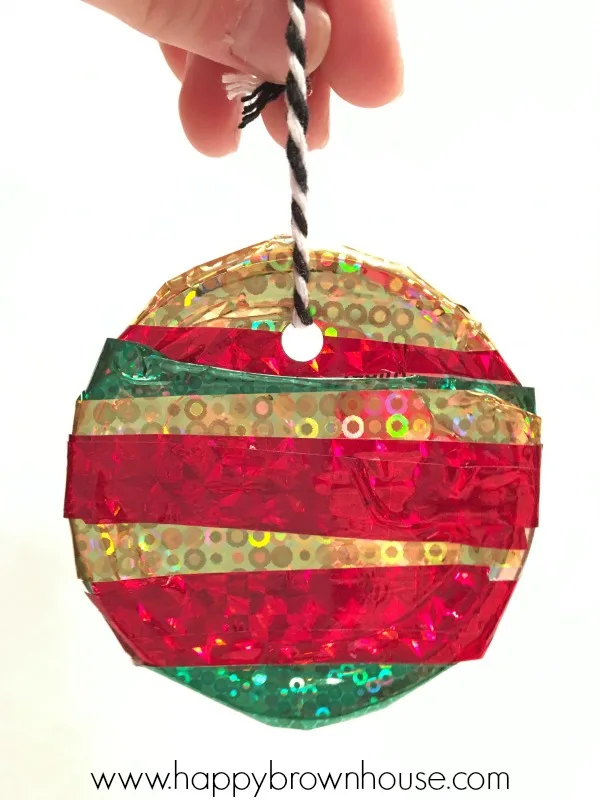 This Kid-Made Washi Tape Mason Jar Lid Ornament is adorable and so simple to make for Christmas. This homemade ornament is perfect for working on fine motor skills. The best part is I already have all the mason jar lids and washi tape for this kids Christmas ornament craft.