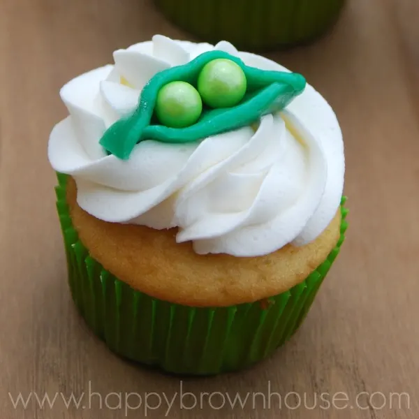 close up of vanilla cupcake with white buttercream swirls and homemade candy peapod cupcake topper for Two Peas in a Pod Cupcake