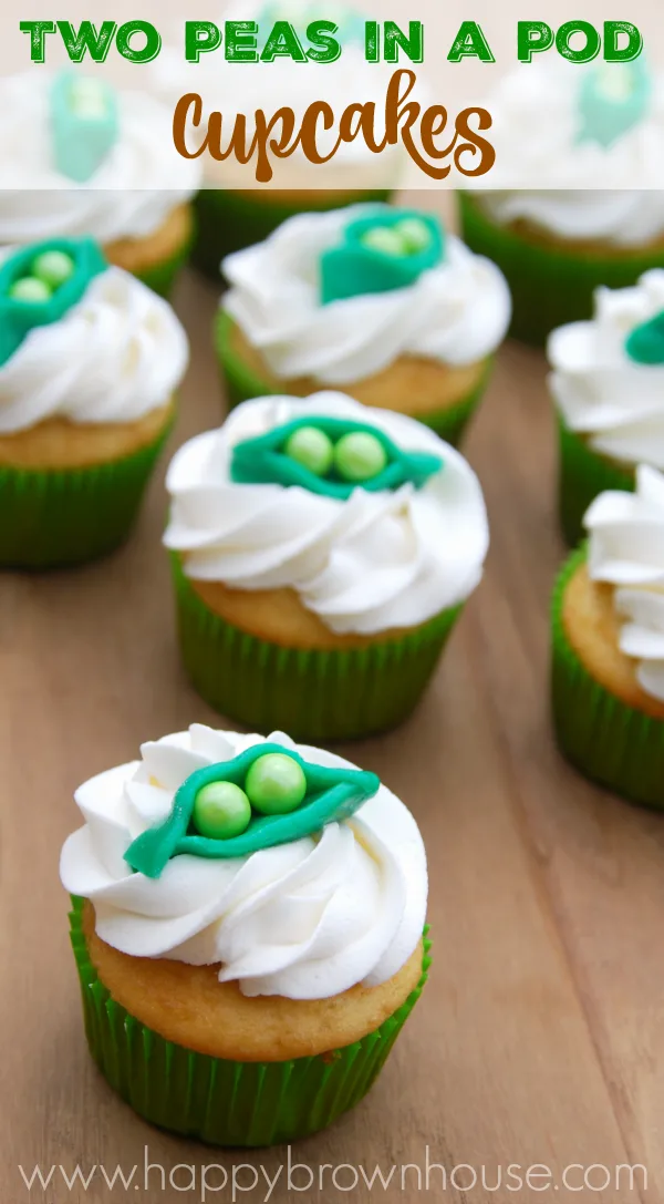 close up of vanilla cupcakes in green cupcake liners topped with white buttercream icing swirl and homemade candy peapod cupcake toppers