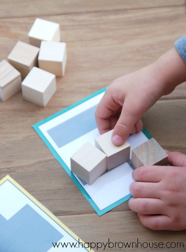 child\'s hands placing one inch wooden cubes on a printable card for the Block Shadows busy bag 