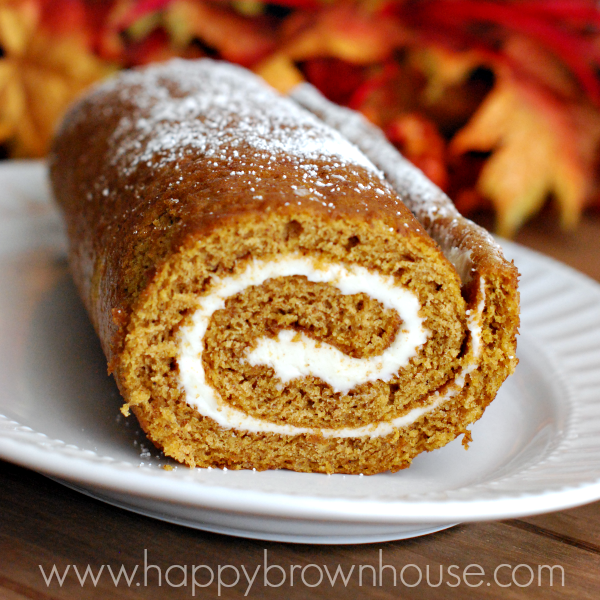 thin pumpkin cake with cream cheese filling rolled up in a spiral on a white platter