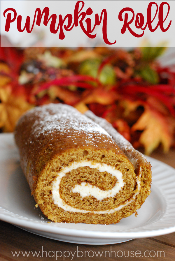 close up of a thin spiraled pumpkin cake roll with cream cheese filling on a white plate, fall leaves in the background