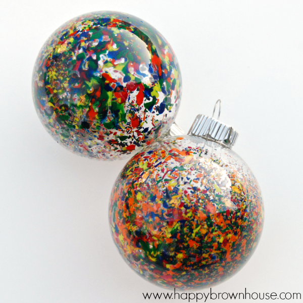 Two glass ornament balls filled with colorful crayon shavings that have been melted inside the ornament