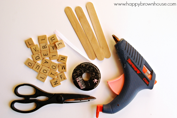 craft materials to make Scrabble Tile Ornaments: scrabble tiles, jumbo craft stick, hot glue gun, ribbon, and scissors