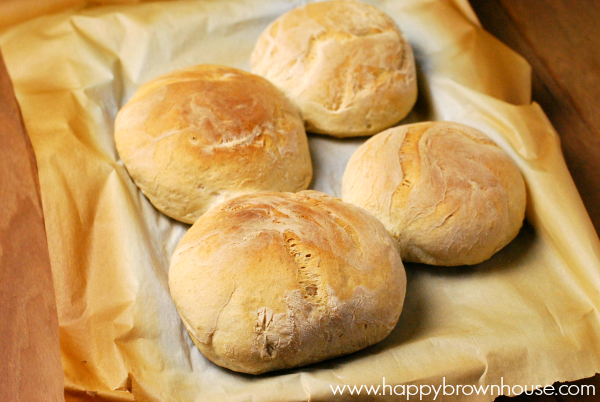 Homemade bread bowls sitting on a parchment paper lined pan