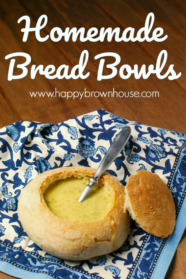 Homemade bread bowl with Broccoli Cheese soup and a spoon resting on the side, sitting on a blue napkin and a brown table background