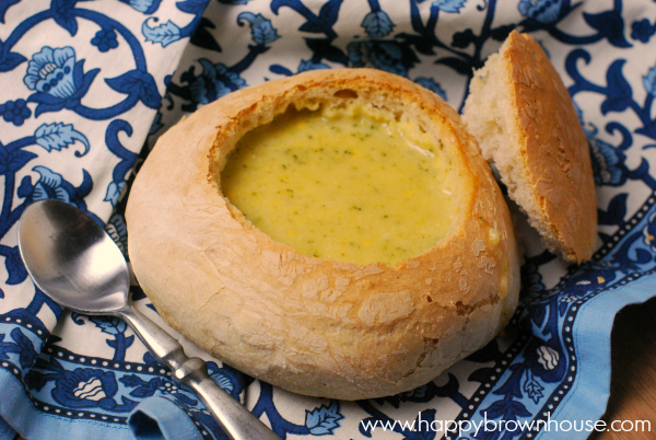 homemade bread bowls with broccoli cheese soup on a blue and white cloth napkin