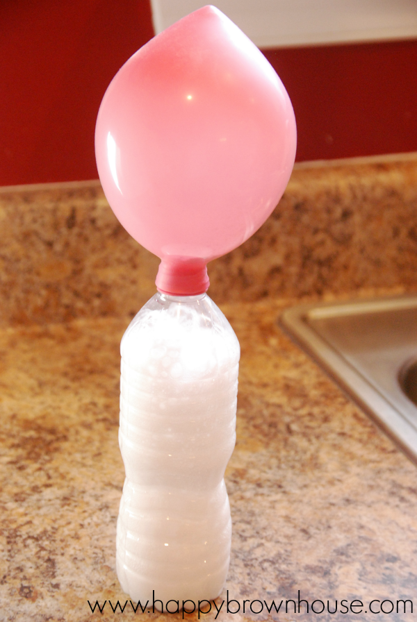 pink inflated balloon attached to a water bottle with fizz from a baking soda and vinegar reaction