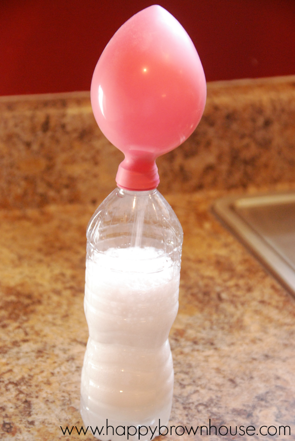 partially inflated balloon attached to a water bottle with fizz from a baking soda and vinegar reaction inside