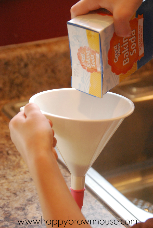 pouring baking soda into a funnel attached to a balloon