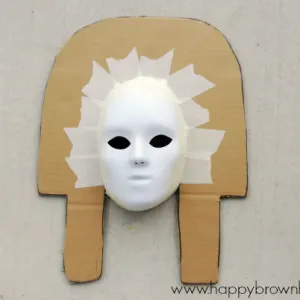 cut cardboard shape and attach mask to prepare for paper mache