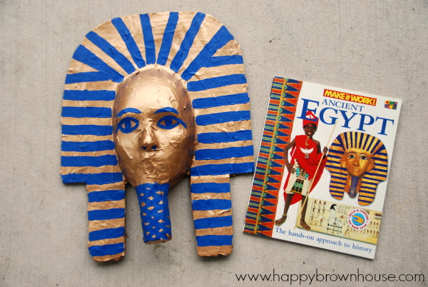 paper mache King Tut Burial Mask craft painted gold and blue next to an Ancient Egypt craft idea book