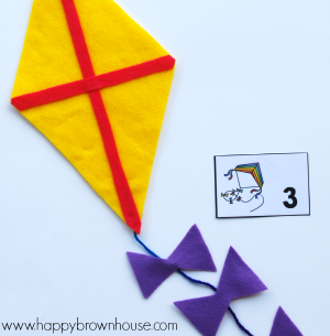 Yellow and red felt kite with purple bows next to a kite counting card printable