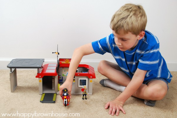 boy in blue shirt playing with PLAYMOBIL Take Along Fire Station for pretend play all afternoon