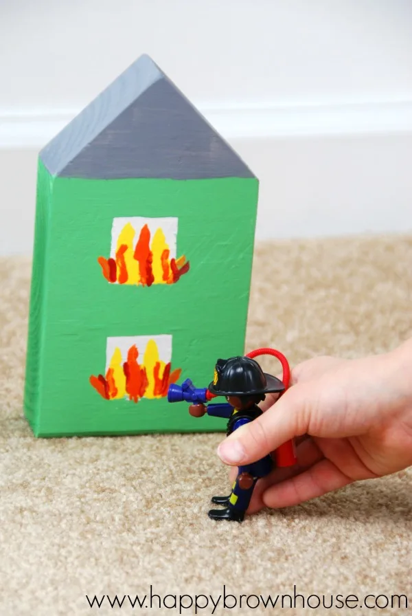 Playing pretend with PLAYMOBIL fire fighter figure and a wooden block house