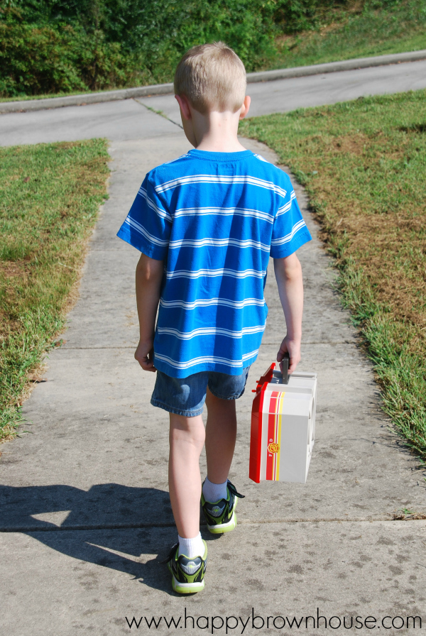 Boy walking on sidewalk with portable PLAYMOBIL Take Along Fire Station