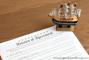 Close up of a free printable Articles of Agreement and a small pirate ship figurine