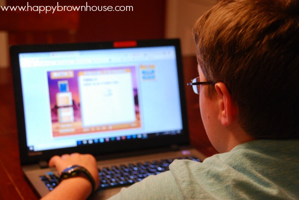 rear side view of a child wearing glasses looking at a computer screen with a math lesson on the screen