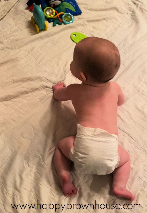 overhead view of a baby crawling around in a diaper on a quilt