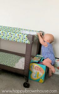 Determined baby trying to climb over diaper boxes to get in her pack and play travel bed.