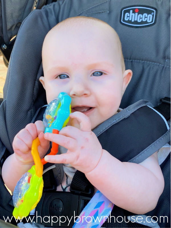 Baby sitting in a stroller holding a rattle