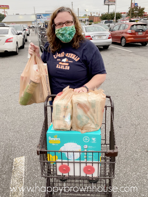 Woman in a mask, pushing a grocery cart in the parking lot