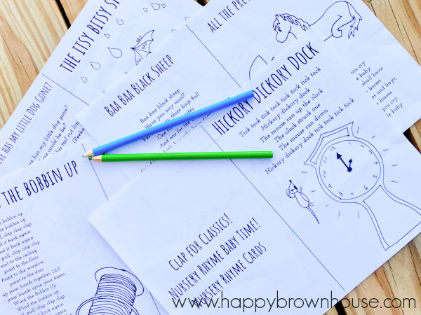 Pieces of paper fanned out on display with green and blue colored pencils on top. Nursery rhyme words and illustrations are on the papers.