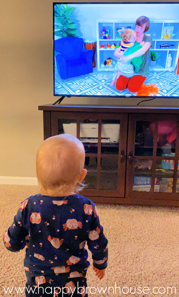 Toddler standing in front of a television watching an online music class