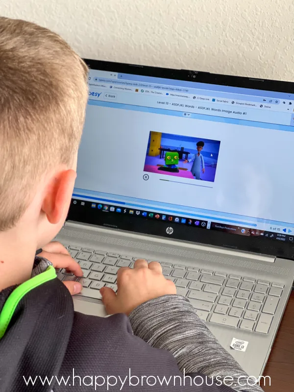 rear side view of a child typing on a laptop keyboard during a homeschool typing lesson