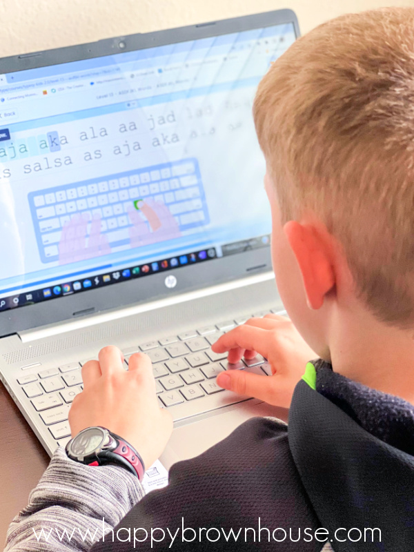 rear side view of a child typing on a laptop with a Typesy homeschool typing lesson on the screen