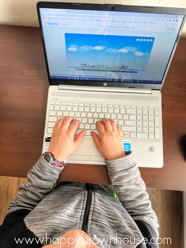 overhead view of child\'s hands typing on a laptop computer keyboard